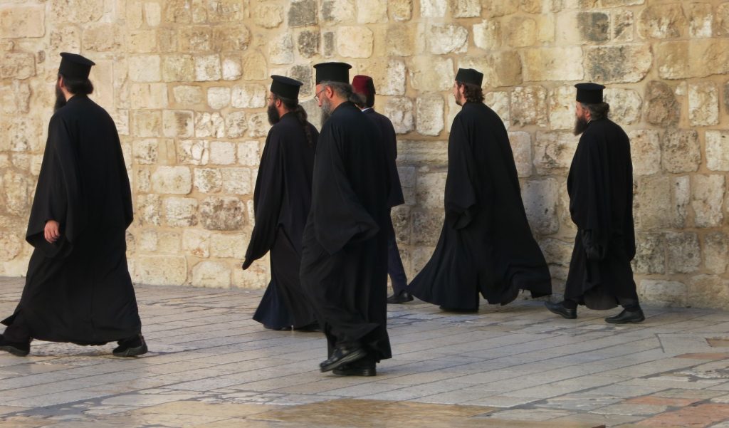 Six priests in long black robes, with beards and flat-topped hats.