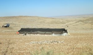 A brown plain with a long low tent in the middle.