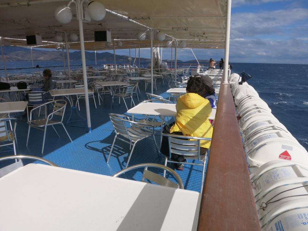 Looking along a deck with open sides and a roof, filled with tables and chairs.