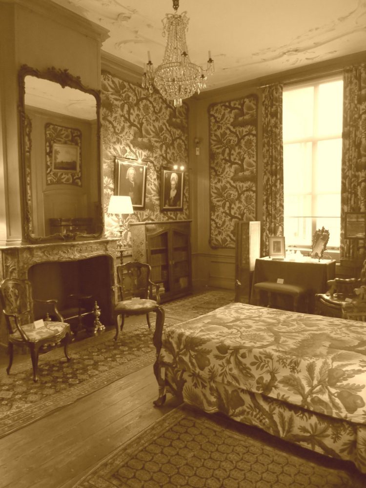 An elegant bedroom in the van Loon Museum: flowery wallpaper, crystal chandelier.