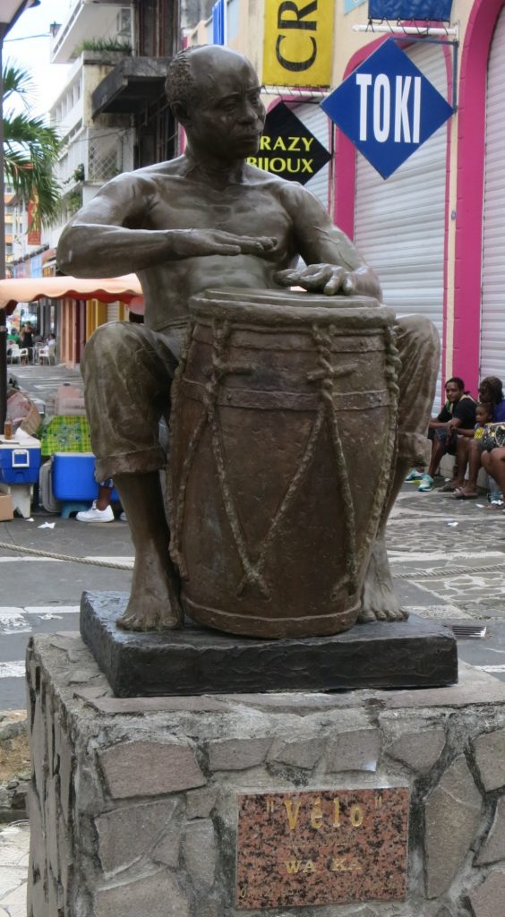 The statue showing a man playing a large drum