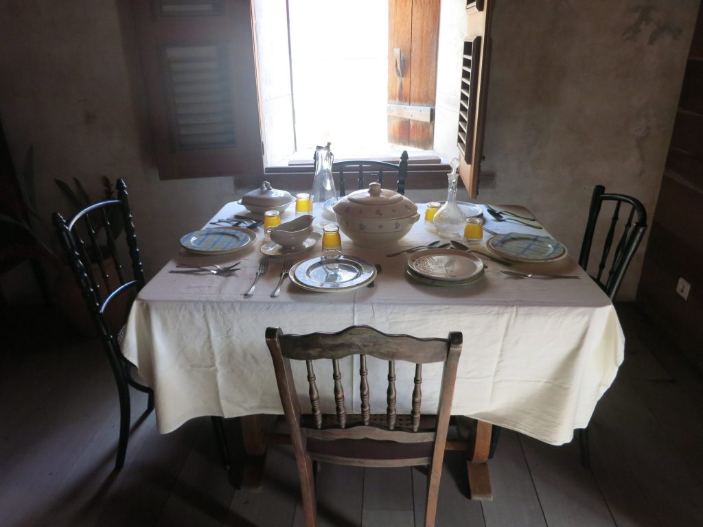 The coffee plantation master's house interior view, showing a dining table with four chairs, all set for a meal