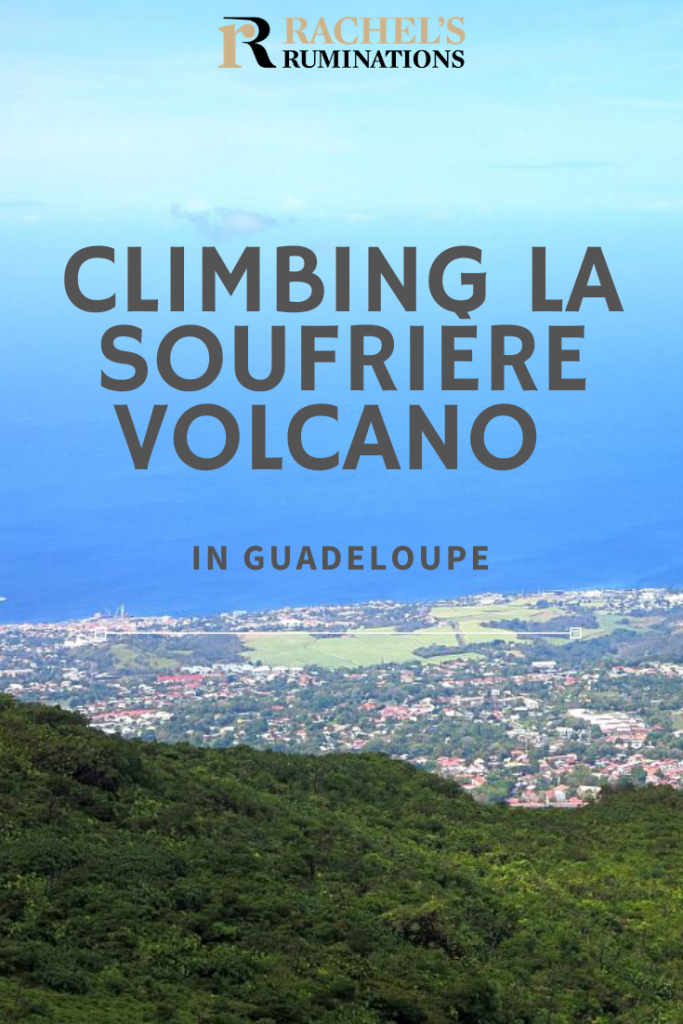 Pinnable image
Text: Climbing La Soufriere Volcano in Guadeloupe
Image: a view down over land and villages far below and the very blue sea beyond, blending with the blue sky.