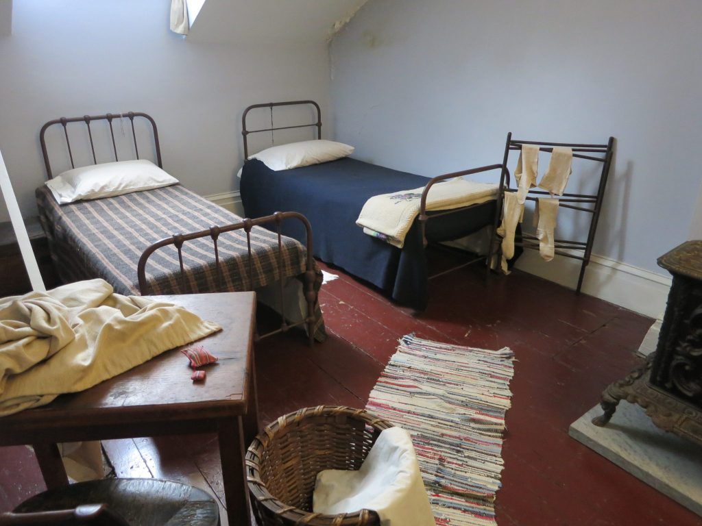 In Merchant's House Museum, a view of the attic room of the servants, showing two plain metal twin beds and modest furnishings