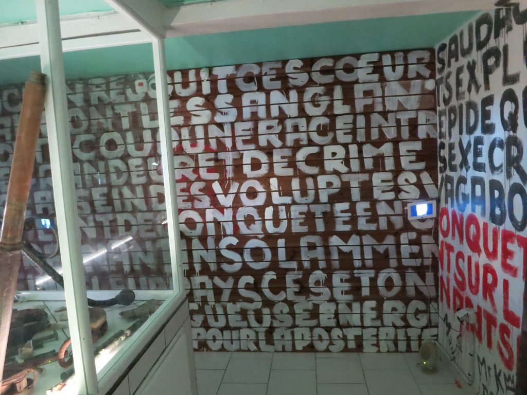 The wall is covered in closely-painted capitalized words in French: volupte, sanglant, etc. in the pirates room of Kreol West Indies