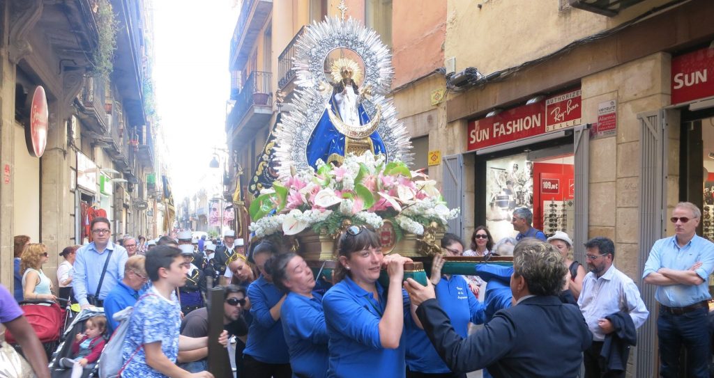 In old Barcelona, the women carry the Mary figure on their shoulders in Barcelona. The figure is decorared with a crown and surrounded by flowers.