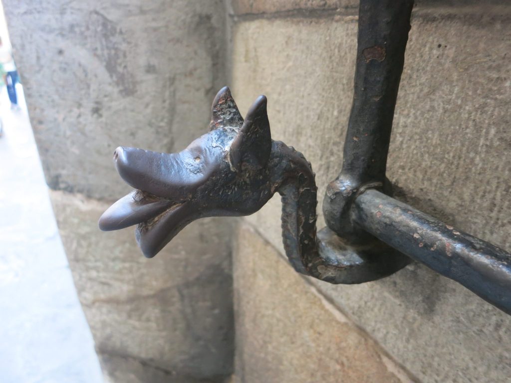 close-up of a dragon figure edging the bars over a window in Barcelona