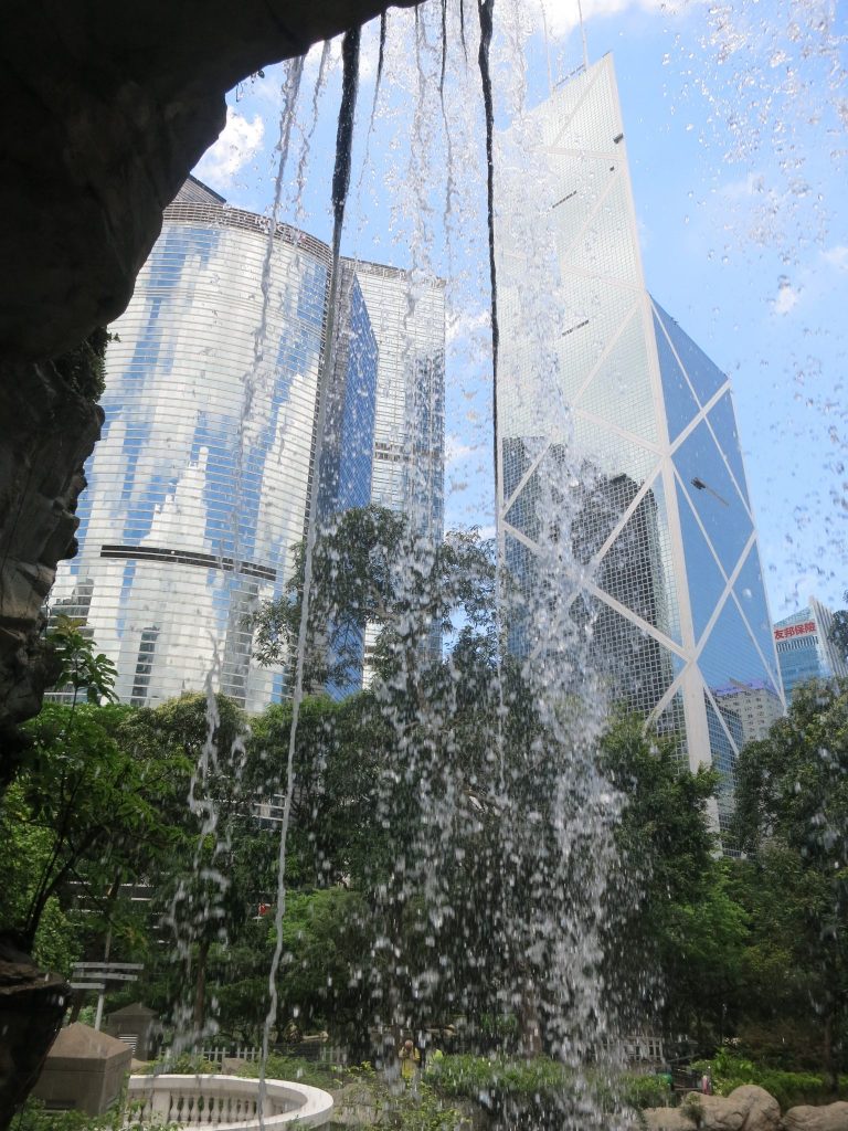 view of some shiny glass buildings, distorted by the waterfall