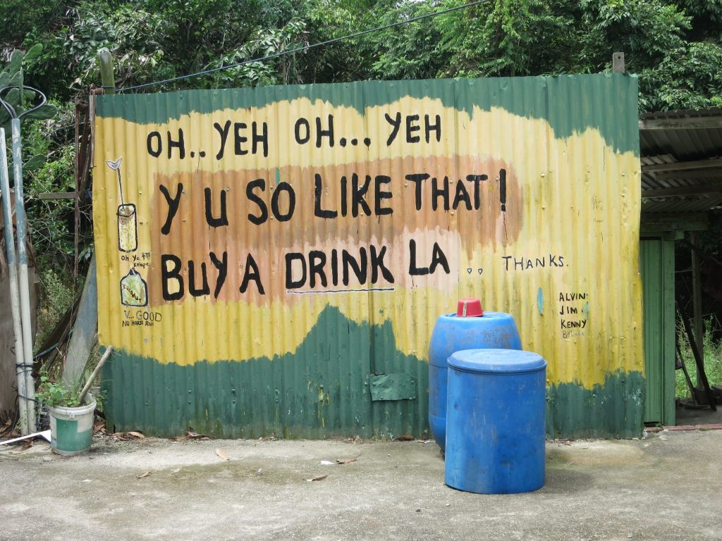 a handpainted sign outside a drink stand on Pulau Ubin reads "OH .. YEH OH ... YEH Y U SO LIKE THAT! BUY A DRINK LA."