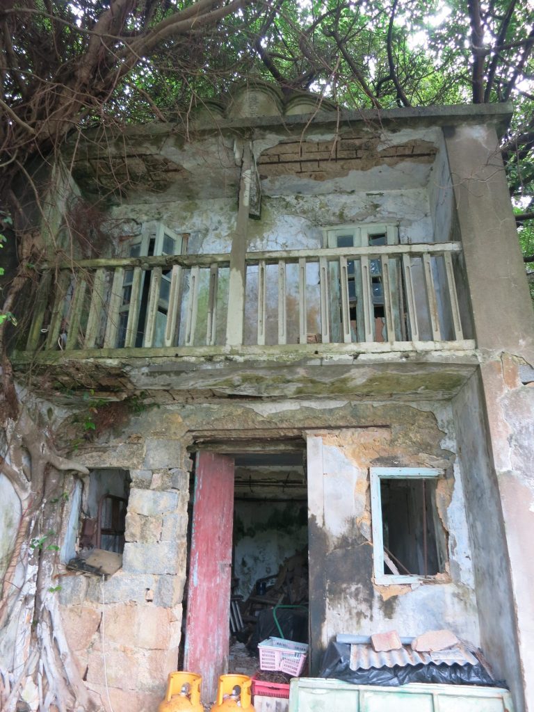 a crumbling two-storey building with a balcony on the upper floor, on Lamma Island