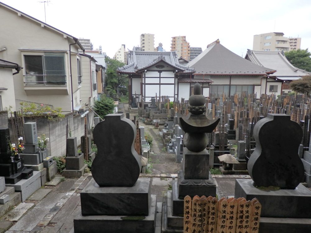 a crowded graveyard with the back of a temple in the background, in Yanaka, Tokyo