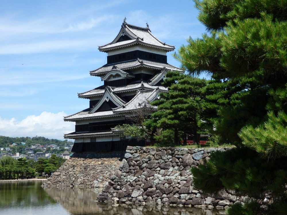 Matsumoto Castle appears to have five storeys, and stands on top of a stone wall above a moat