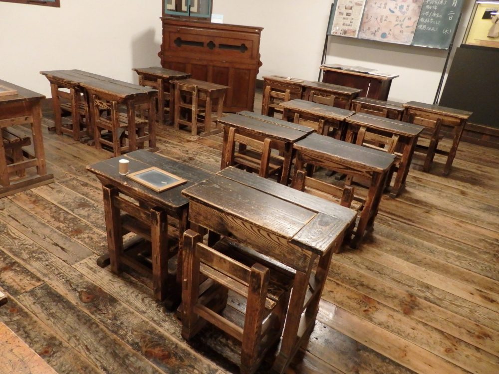 old-fashioned wooden desks are lined up two by two in a classroom in Kaichi School, Matsumoto