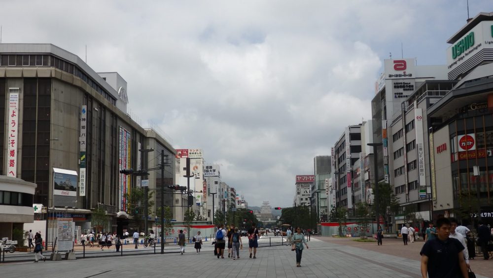 view down a wide street. The castle is visible far in the distance while the street is lined on both sides with unattractive office buildings.