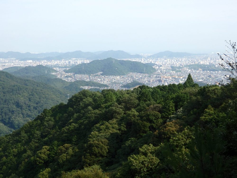 view from the top of the cable car up Mt. Shosha in Himeji: in the near distance is a wooded hill; in the distance the city almost fills the picture.