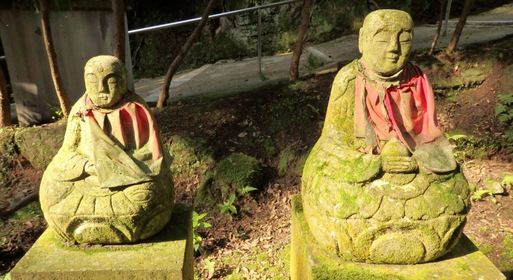  small, simple stone statues in the woods at Engyoji shrine. They are each in a sitting pose and look like monks praying. Each has a faded red cloth tied around its neck.