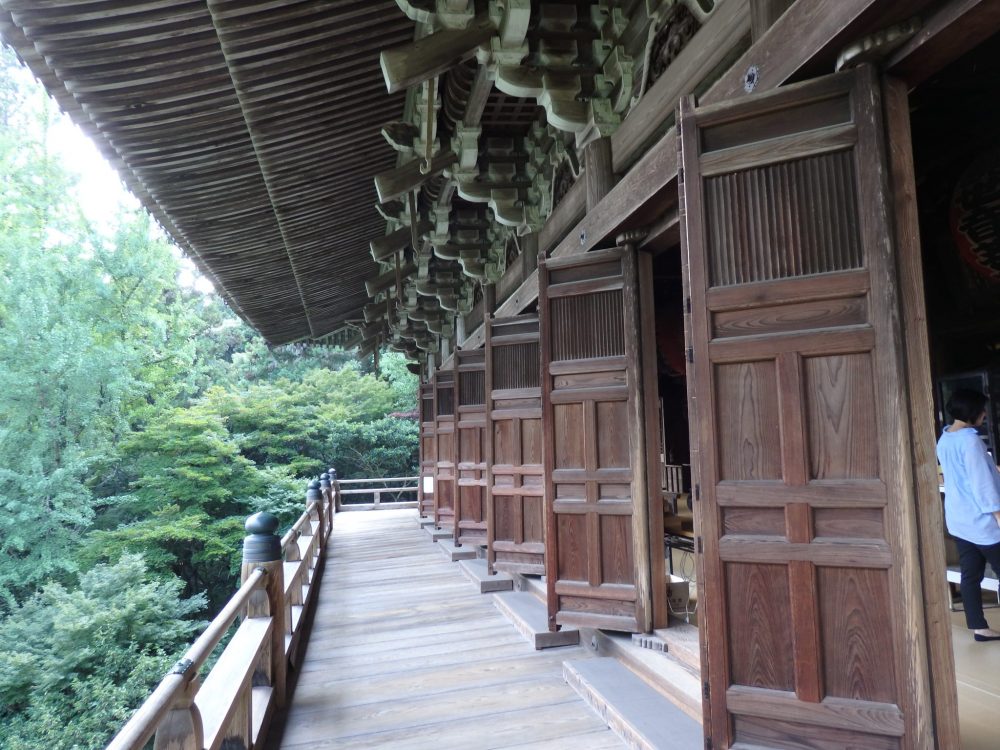 Things to do in Himeji: Engyoji shrine on Mt. Shosha. This view shows a long wooden balcony straight ahead, with an ornate roof above it. On the left is a low railing; on the right a series of large wooden doors, all open to the outside.