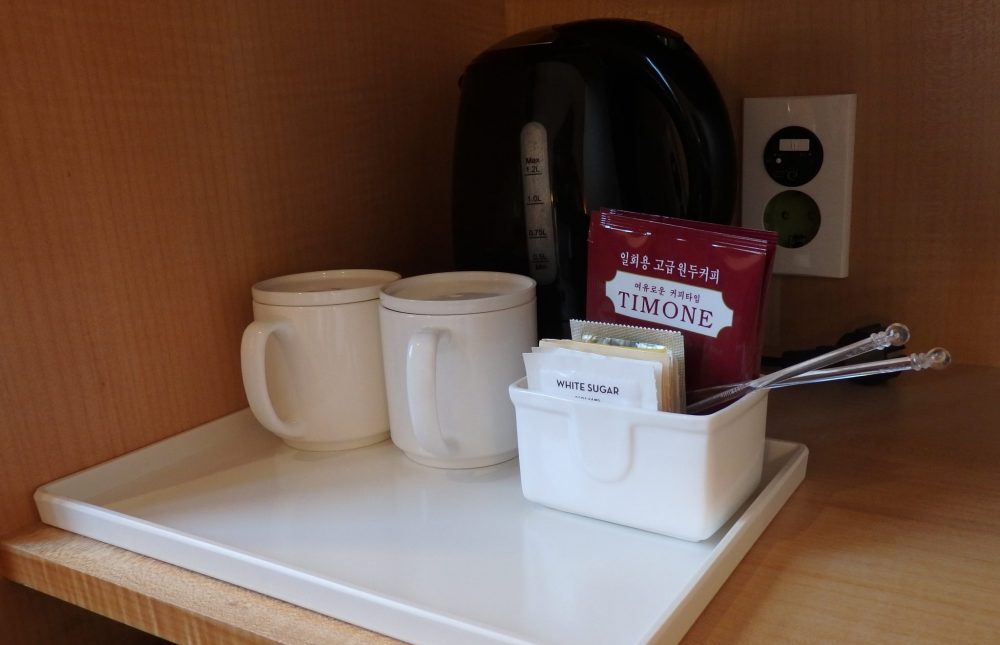 The kettle in the Ibis Hotel is ready, next to an outlet, and supplied with mugs, tea, coffee, sugar and stirrers.