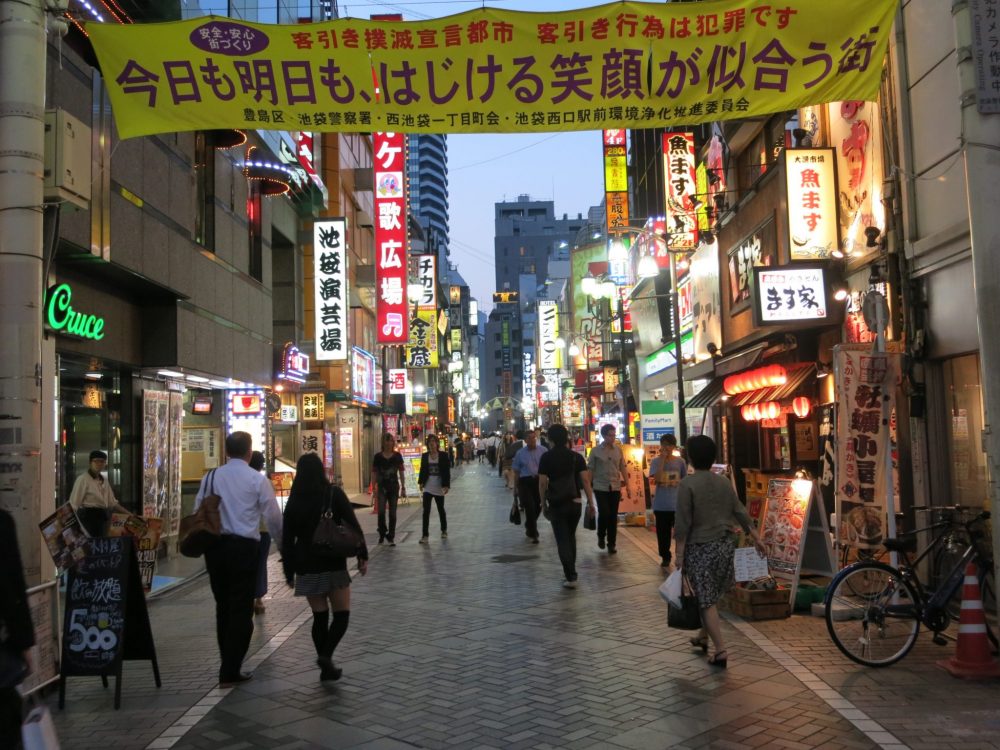 A street around the corner from where I stayed in Tokyo, at dinnertime. The buildings on either side are covered with lighted signs trying to catch the attention of passersby.