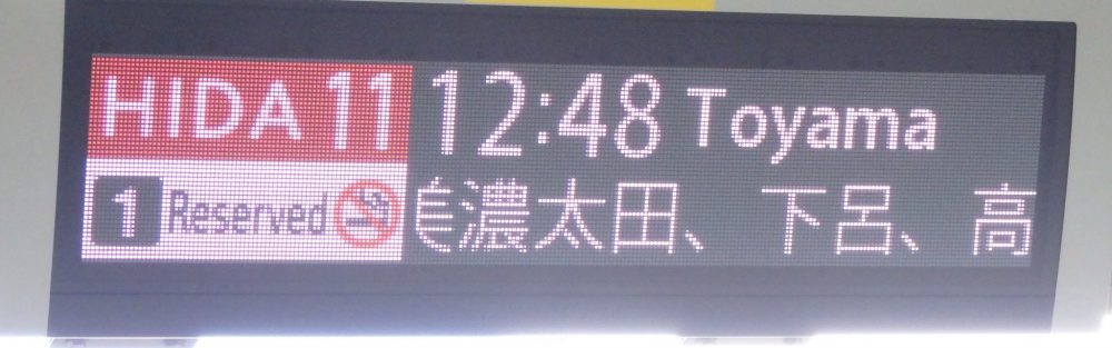 An electronic sign says: Hida 11 train, leaving at 12:48 to Toyama. 