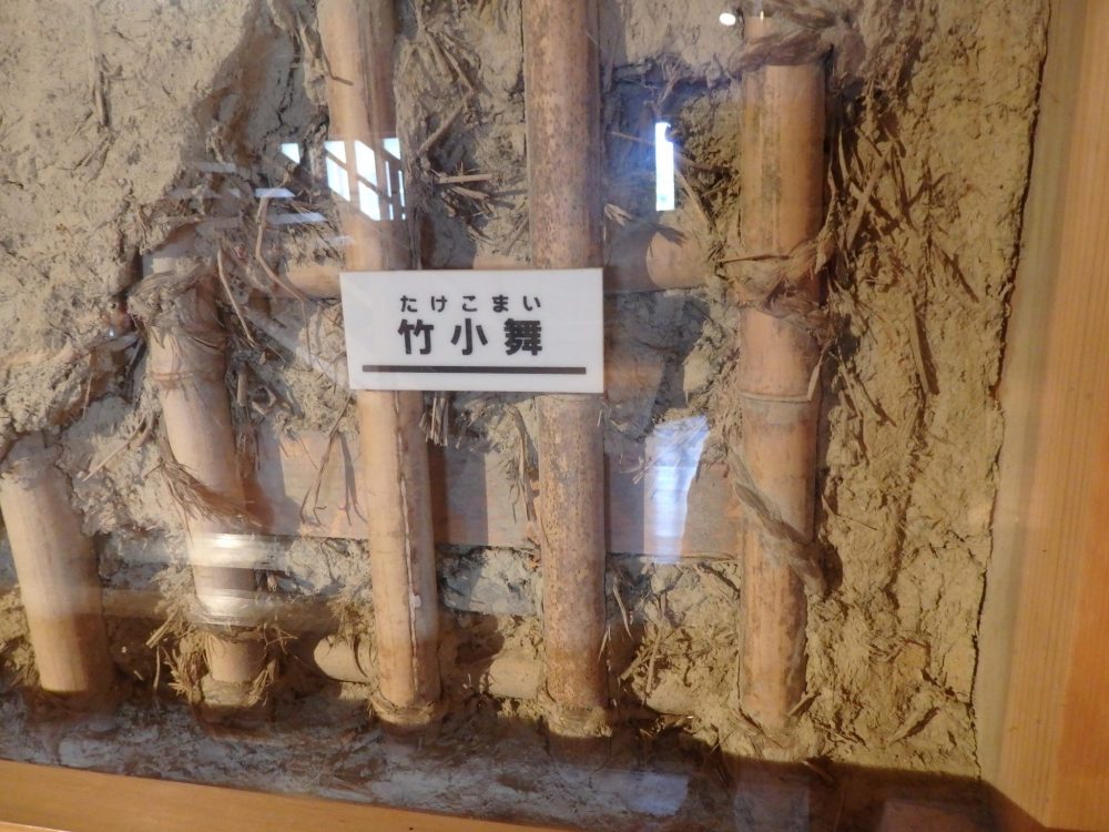 This display in Kanazawa Castle shows how the walls are constructed with sticks, mud, straw and rope. Behind glass are a row of vertical, round stickes and between tthem is mud and straw. 
