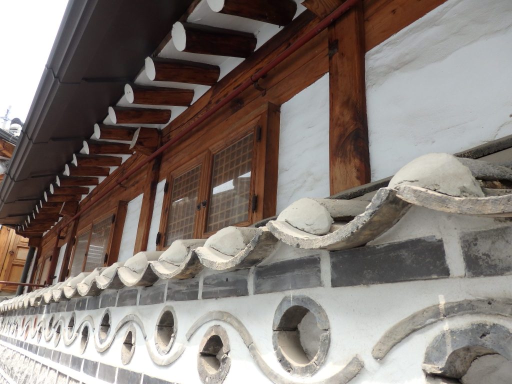 This hanok's wall is decorated with tiles and inset circles of brick.