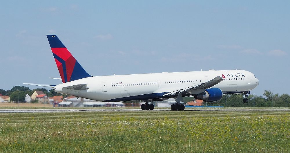 The plane is white except for the blue and red logo on the tail. Its rear wheels are still on the ground, while the nose and front wheel are off the ground.