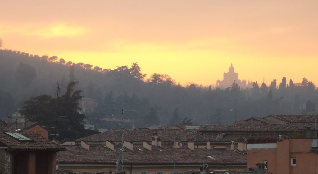 view from the Hotel Touring rooftop terrace at sunset, with the Church of San Luca in the distance.
