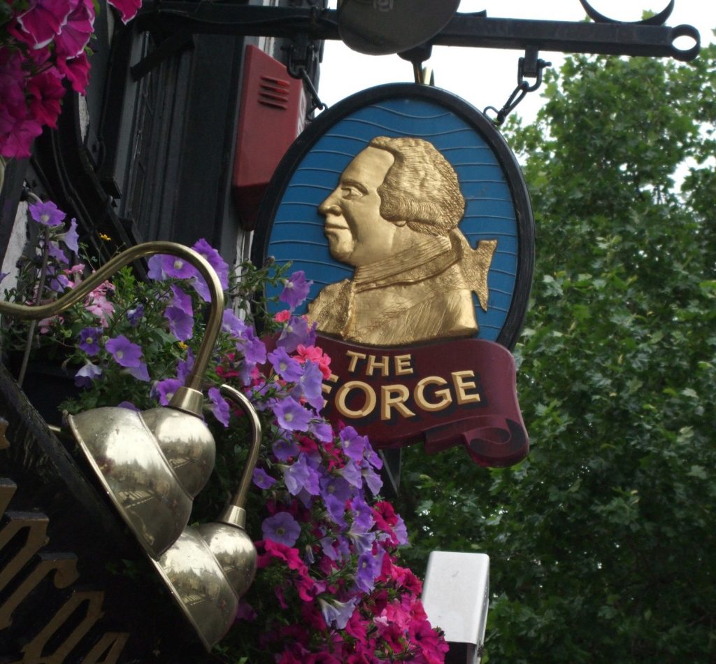 The sign for The George pub in London, surrounded by flowers.