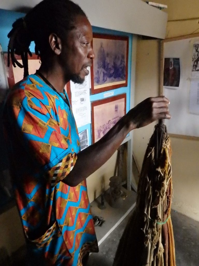 Simon shows us a large, cloth umbrella that a slave had to hold up over Abass's head at all times. Badagry, Nigeria
