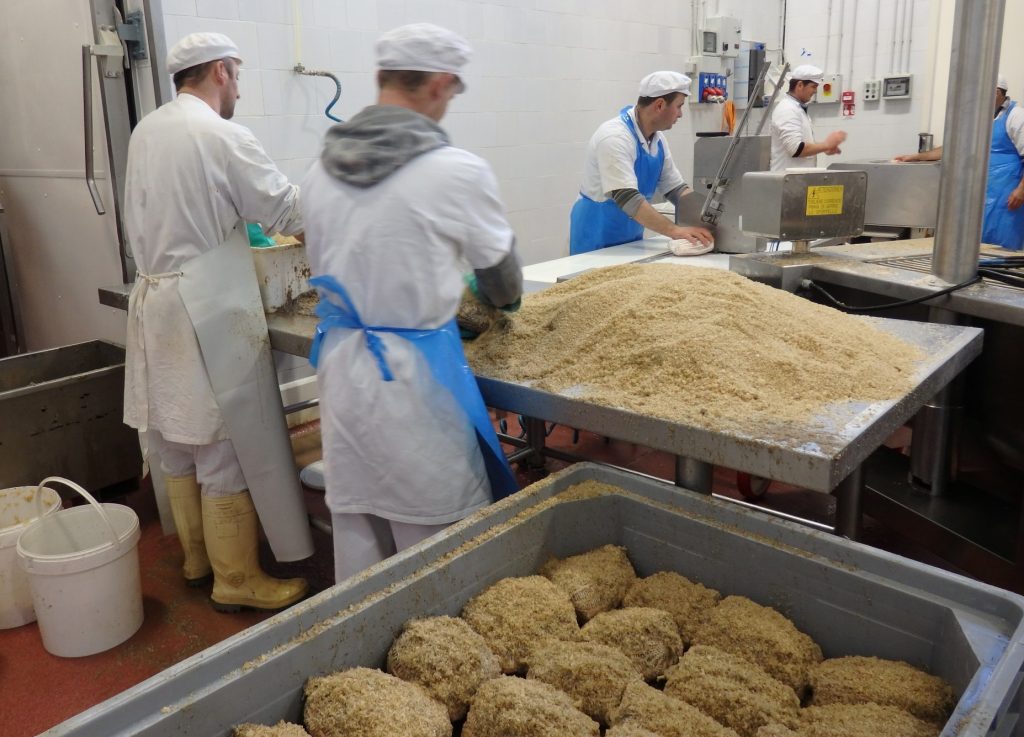 The workers in the back are putting the meat into nets. The ones in front are covering and packing them in salt. Seen on the Italian Days Food Tour.