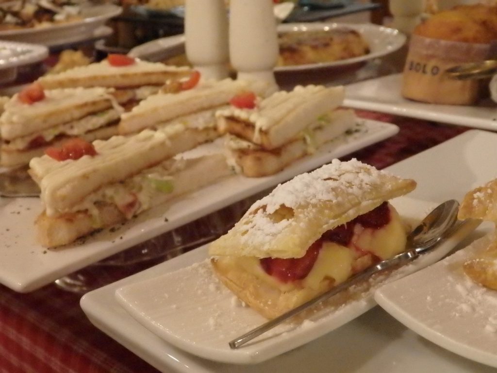 a cream-filled baked item, in front of a sandwich of some sort, with more baked goods in the background, at Hotel El Ciervo