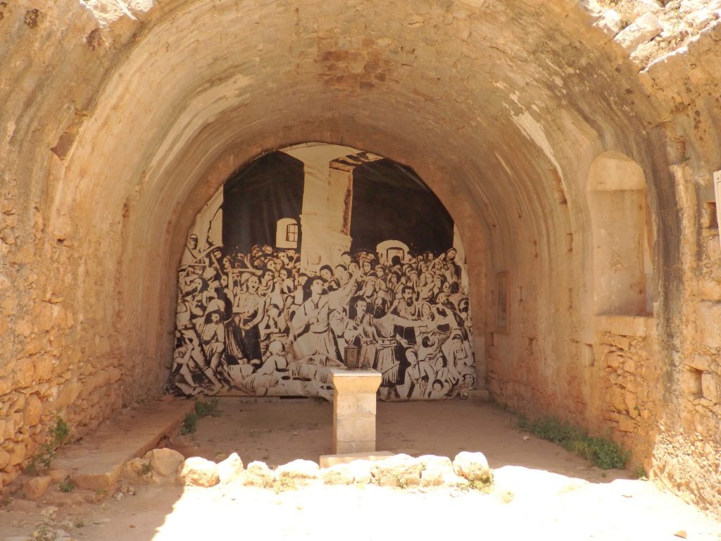 An arched space, the back covered by a black and white depiction of a crowd of people.