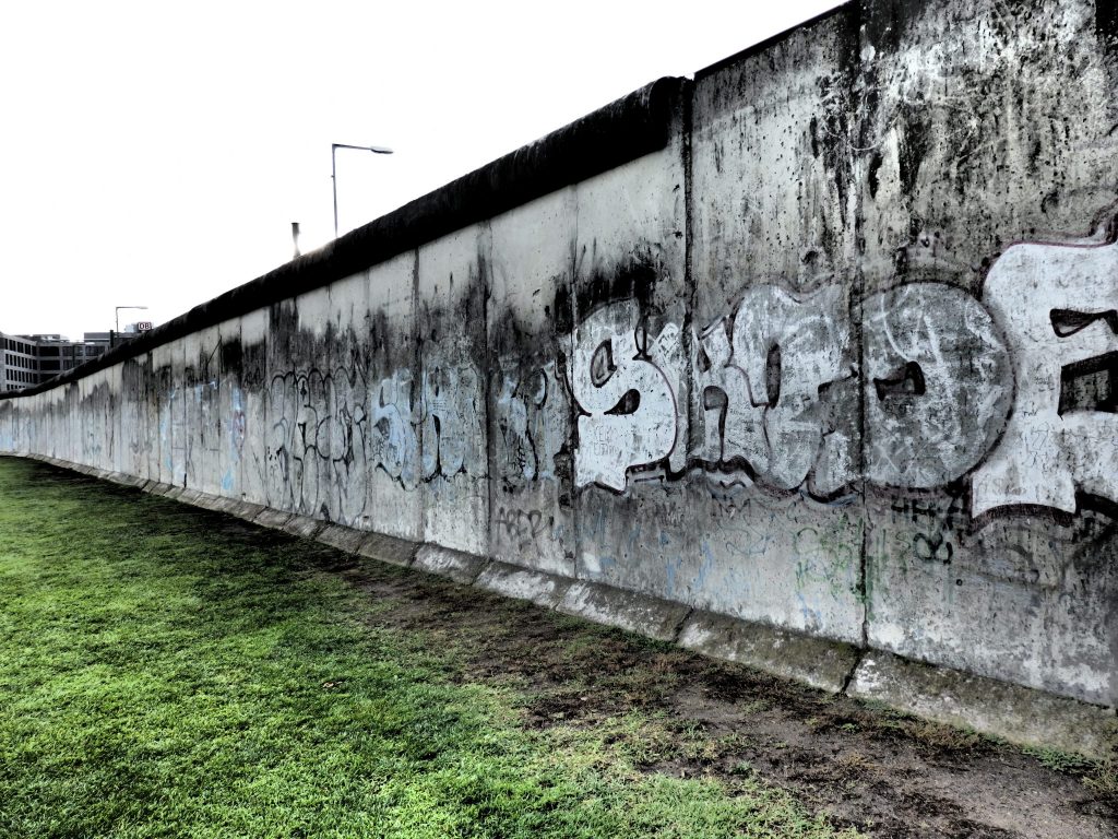 A long dirty grey wall, with painted letters on it.