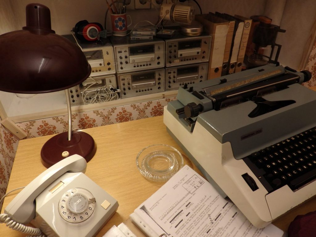 A typewriter, a telephone, some paperwork, and radios or some other sort of equipment.