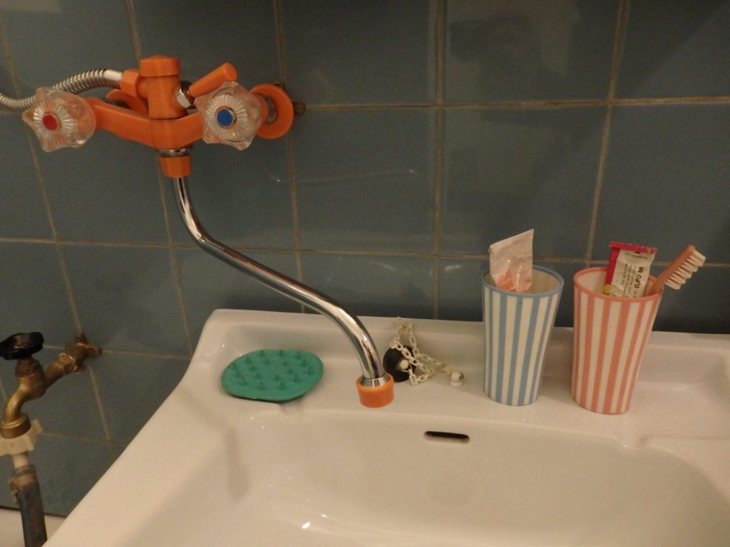 A sink with, above it to the left, a spigot with tubing and two handles in plastic.