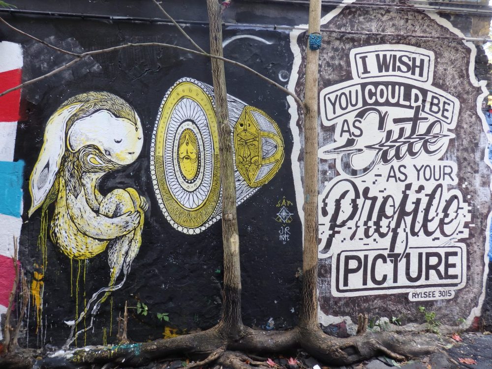 Left, some sort of furry creature with long ears hanging behind, floating next to a cone shaped thing and, on the right, a sign reading "I wish you could be as cute as your profile picture."