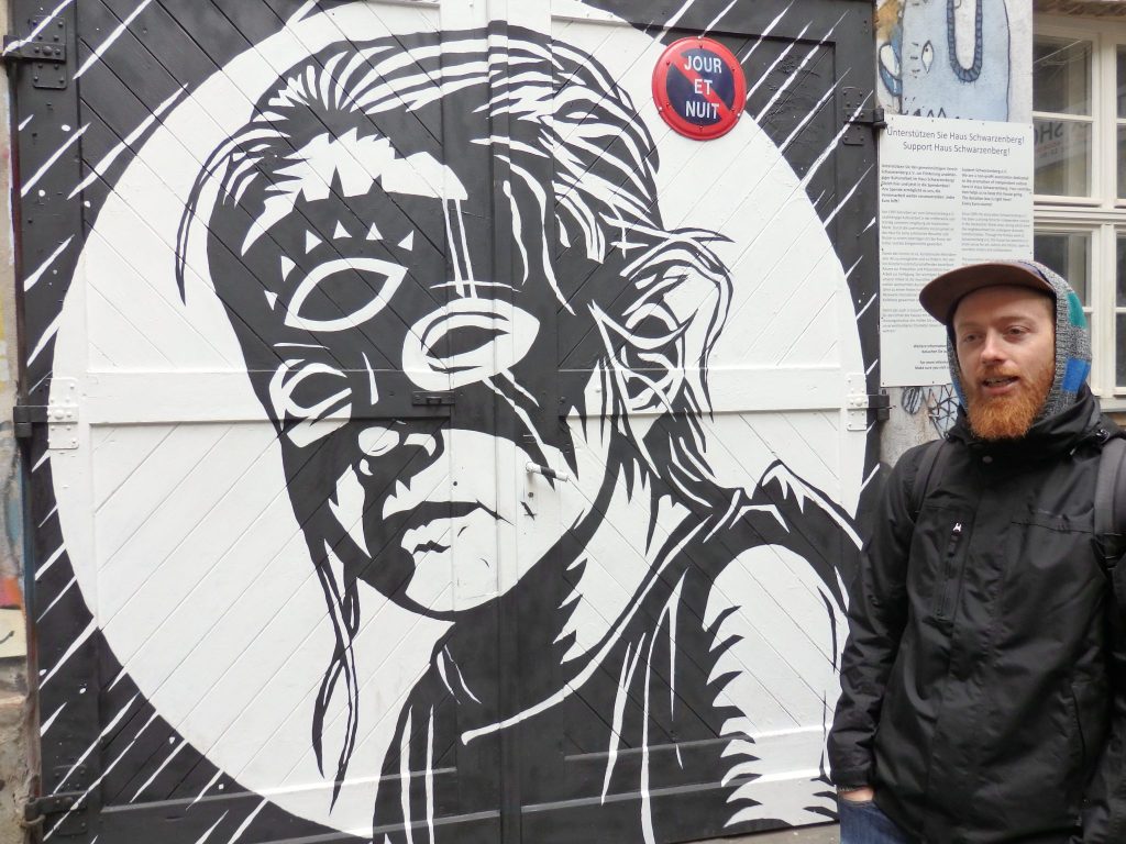 A black-and-white image of a young girl with mask over her eyes that shows a third eye. Red-bearded Ben beside it.