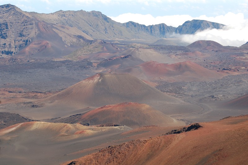 Haleakala Crater in Maui. It's a brown and reddish landscape of hills and valleys, up to higher brown hills in the background. Photo courtesy of Nat Harris.