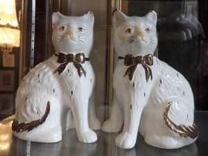 Two porcelain figurines of white cats with bow ties.