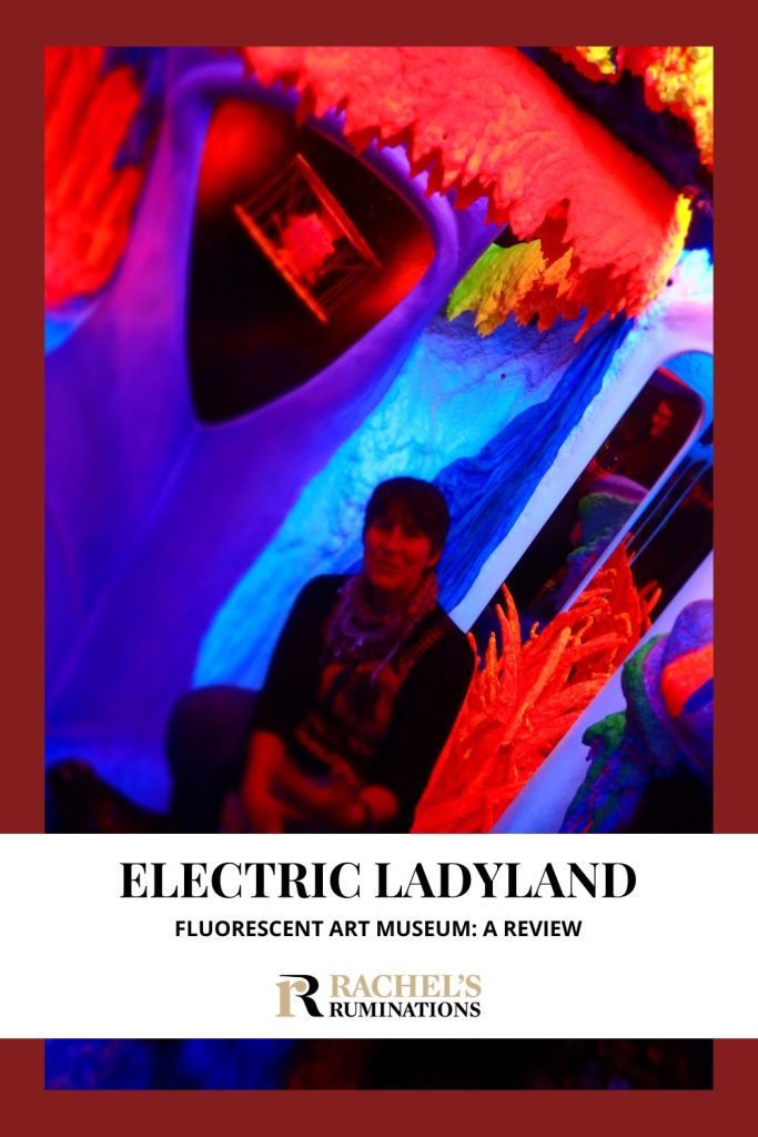 Text: Electric Ladyland fluorescent art museum: A review. Image: Me sitting inside the fluorescent environment.