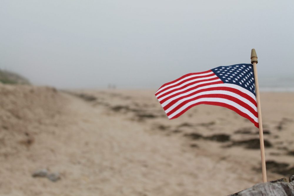 An American flag and the beach stretching behind it.