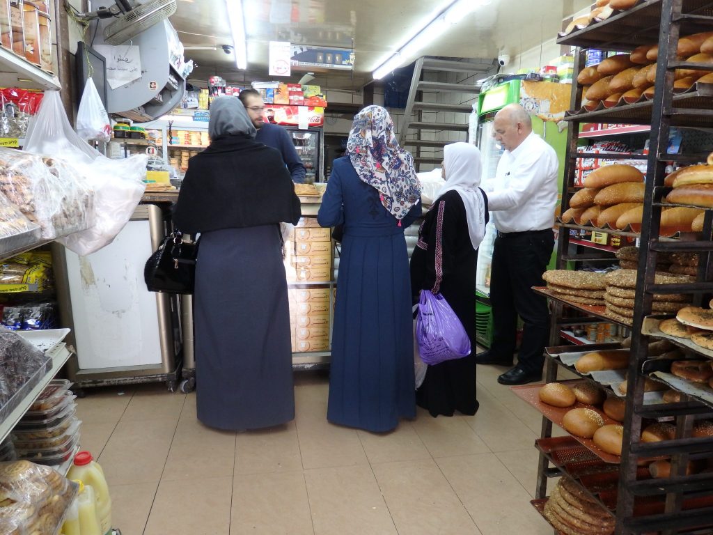 Three women being served at a bakery counter in East Jerusalem.