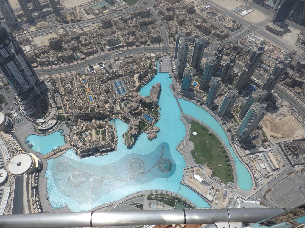 An irregular-shaped blue pool and many buildings of various sizes around it, seen from above.
