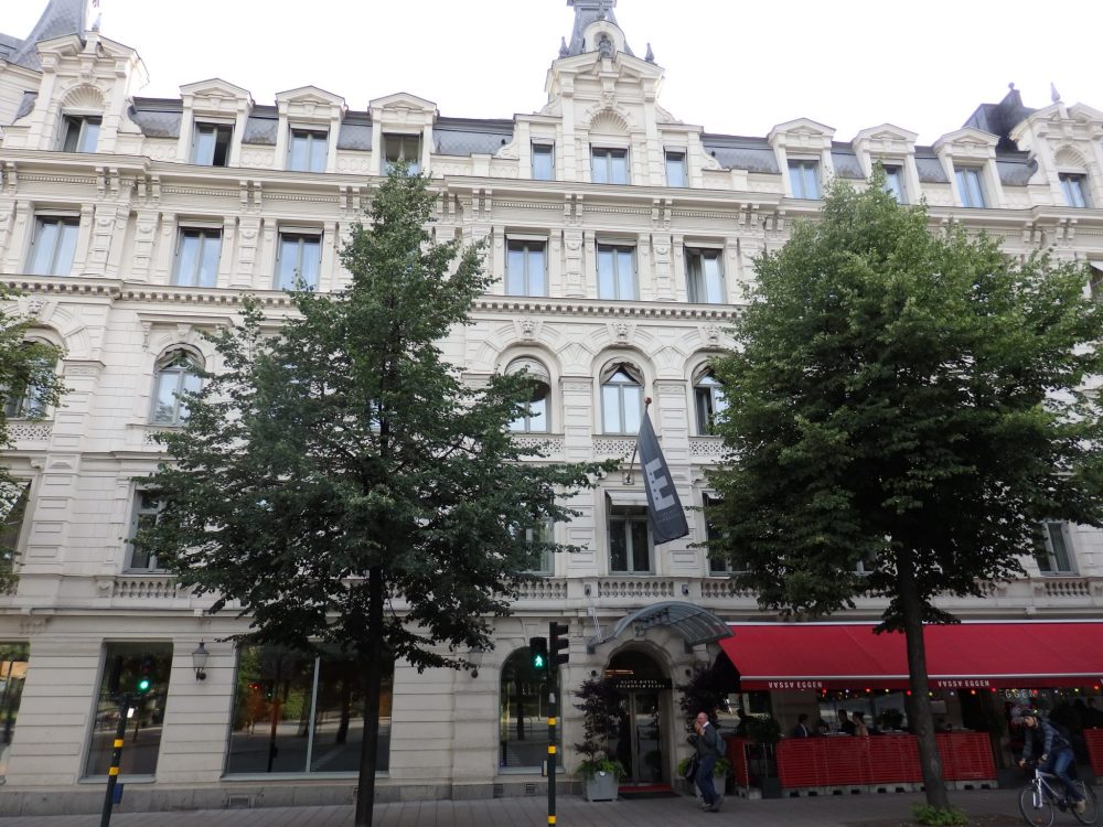 The hotel is about 5 stories tall and white: a classical design with detailed decorations around the windows, some of which are arched at the top.