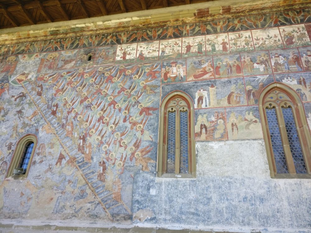 On this exterior wall, on the left, you can see a depiction of the Last Judgement. The winged and haloed watchers above, and the general chaos below. Notice that the devils are portrayed as black. Hmm. At the top, in the white panels, you can make out the Garden of Eden story. Spectacular painted churches of Moldavia.