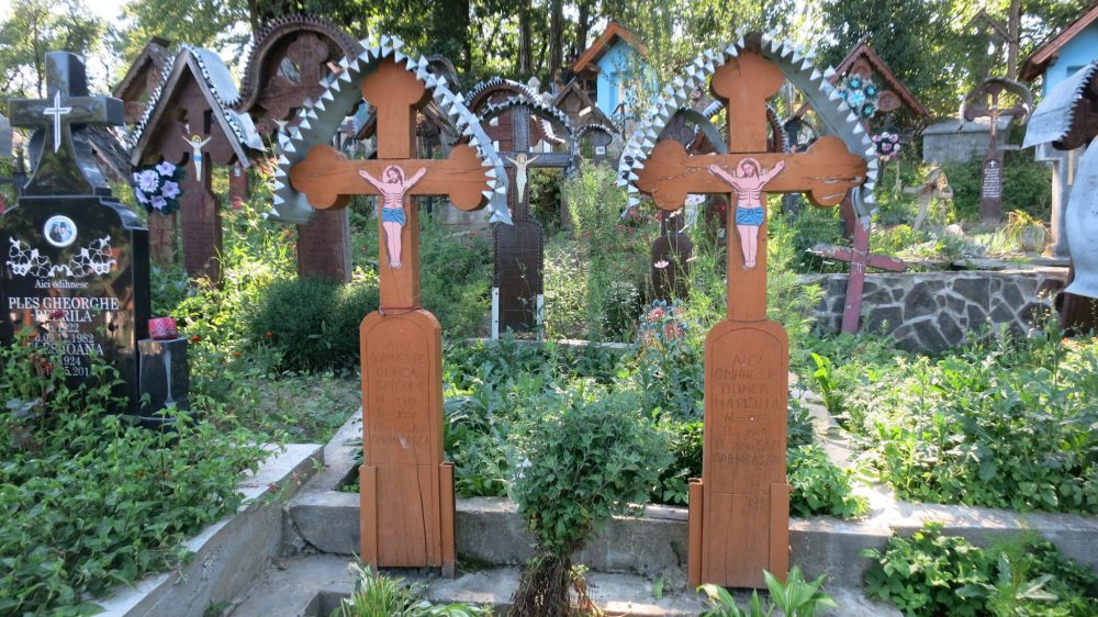 graves in Ieud cemetery, with simply painted crucifixes and metal roofs. The Wooden Churches of Maramures