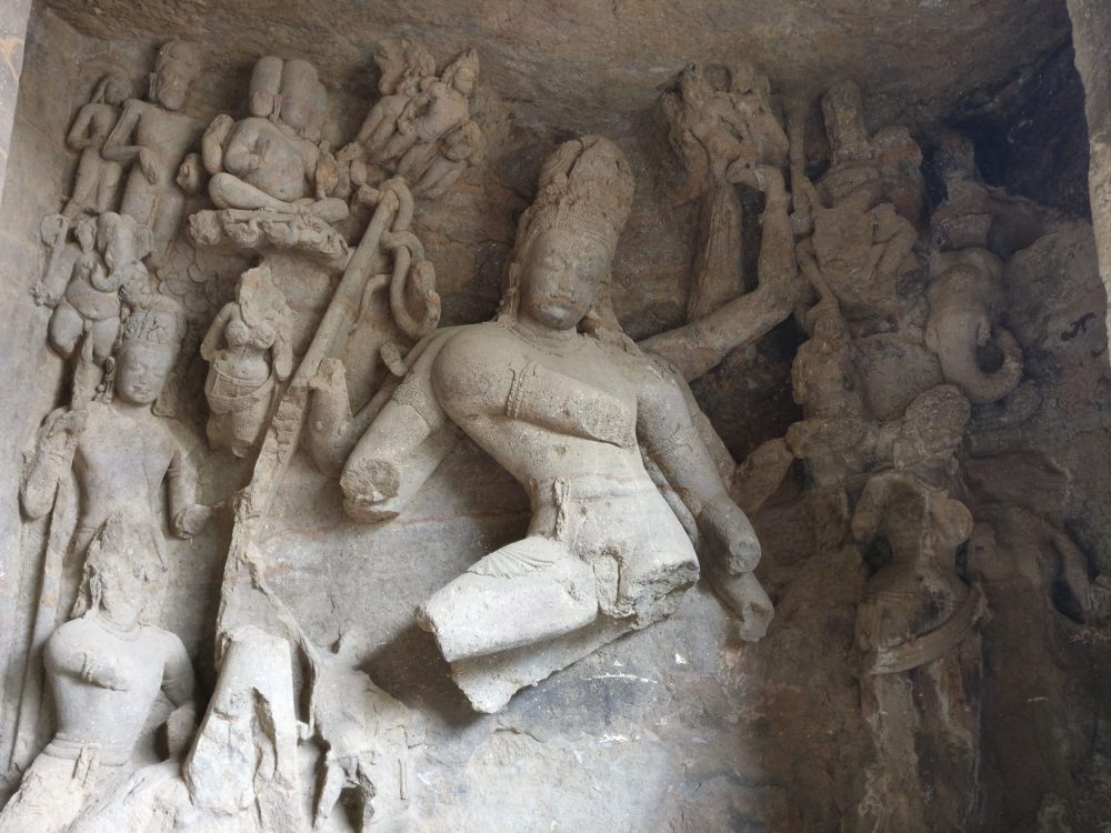 Only the face of the central figure is intact, but it is surrounded on either side by a series of smaller figures, some with human faces and some with elephant faces.