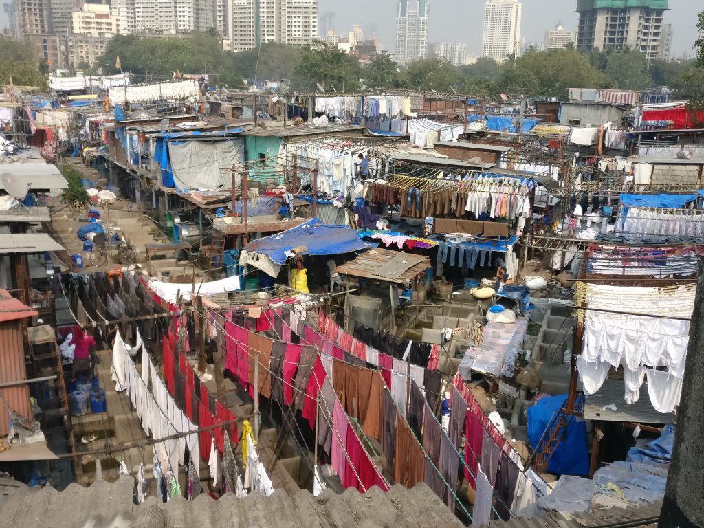 A very cluttered area of small buildings and laundry hanging on lines.