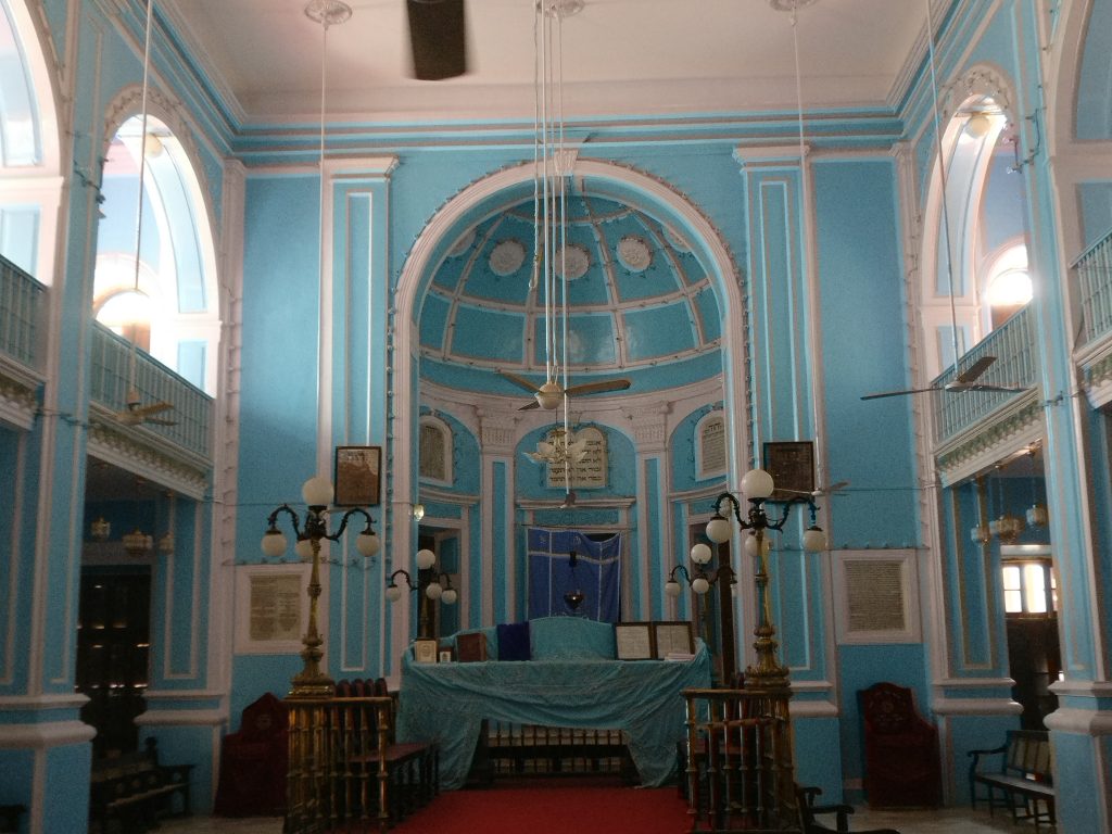 A blue-painted room with arches and windows along both sides and a rounded recess at the far end.